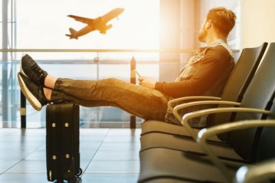 Guy looking out the airport window with a plane taking off